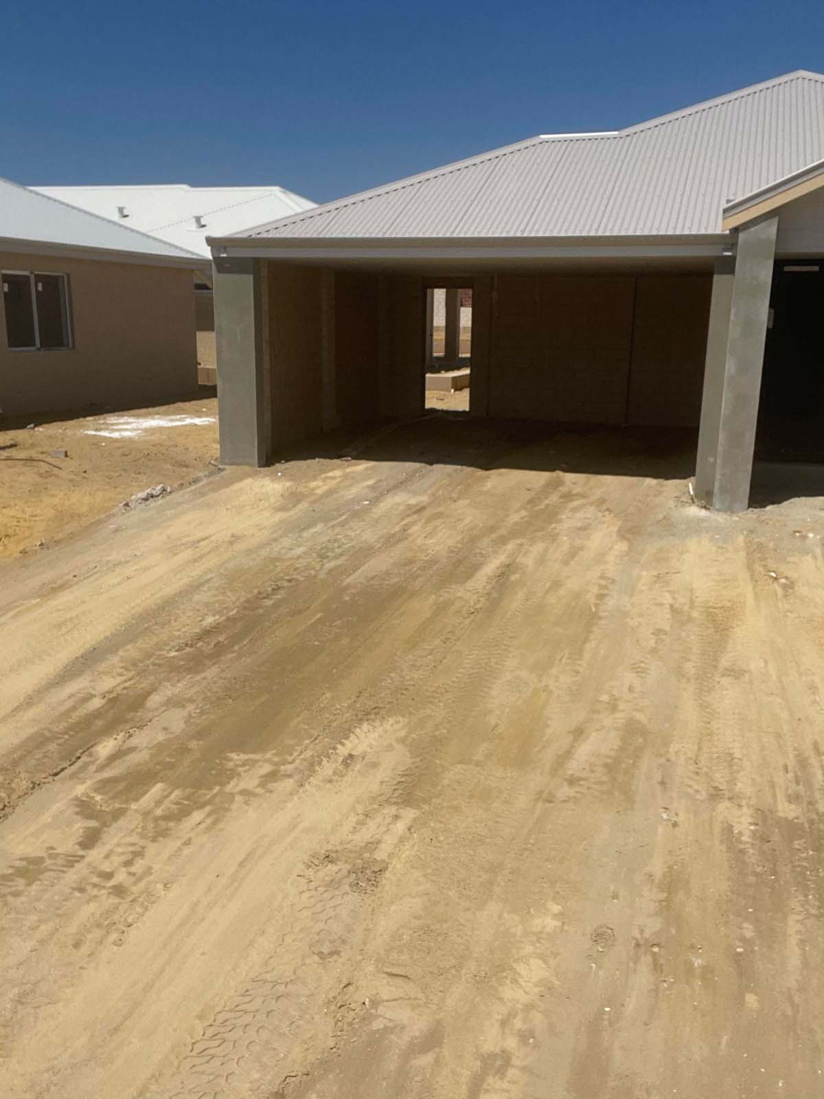 Levelled sandy driveway leading up to a new house's open garage